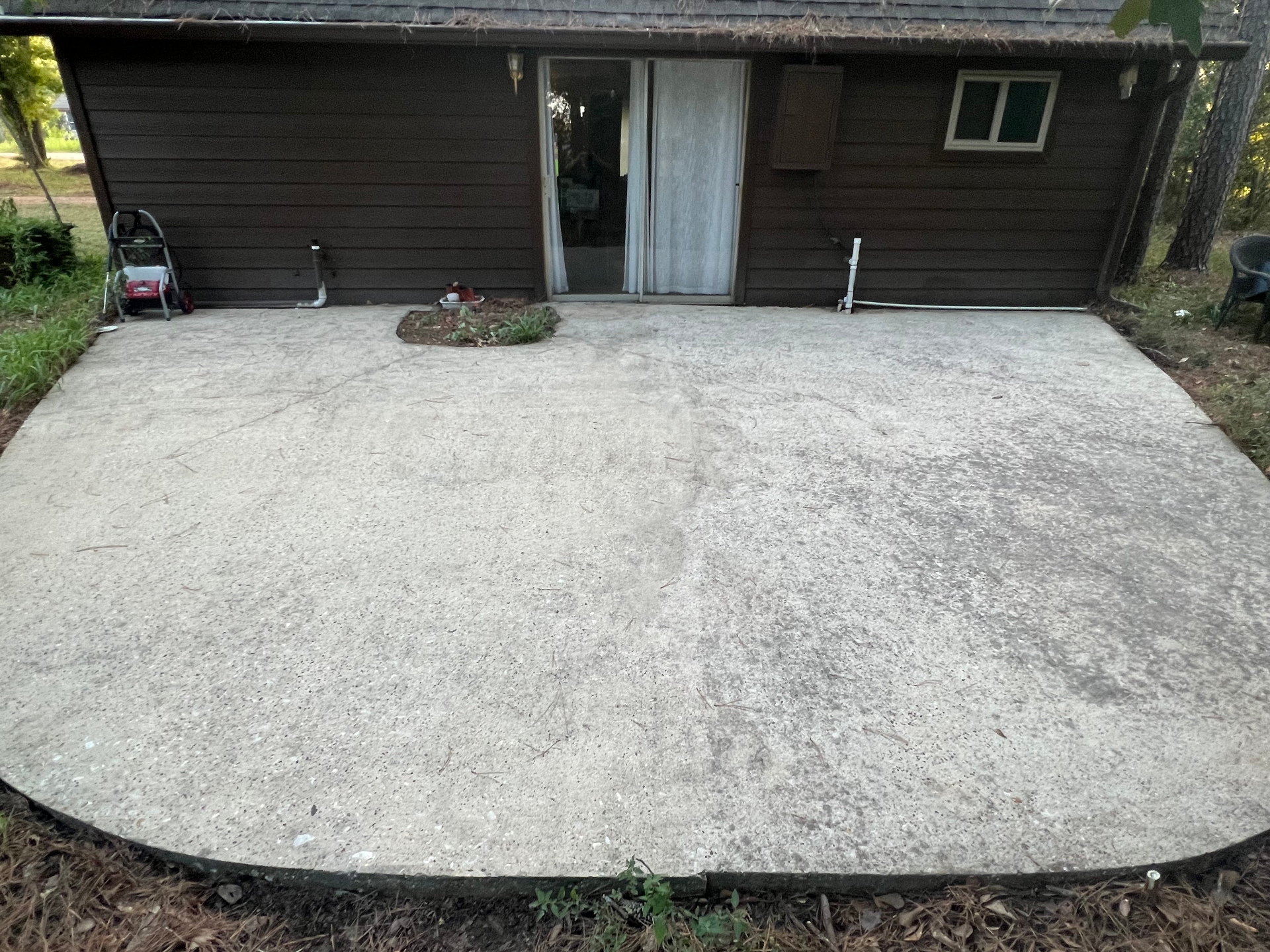 Patio after pressure washing, with left half sealed in single coat and a marked double-coat test square on the right unsealed half