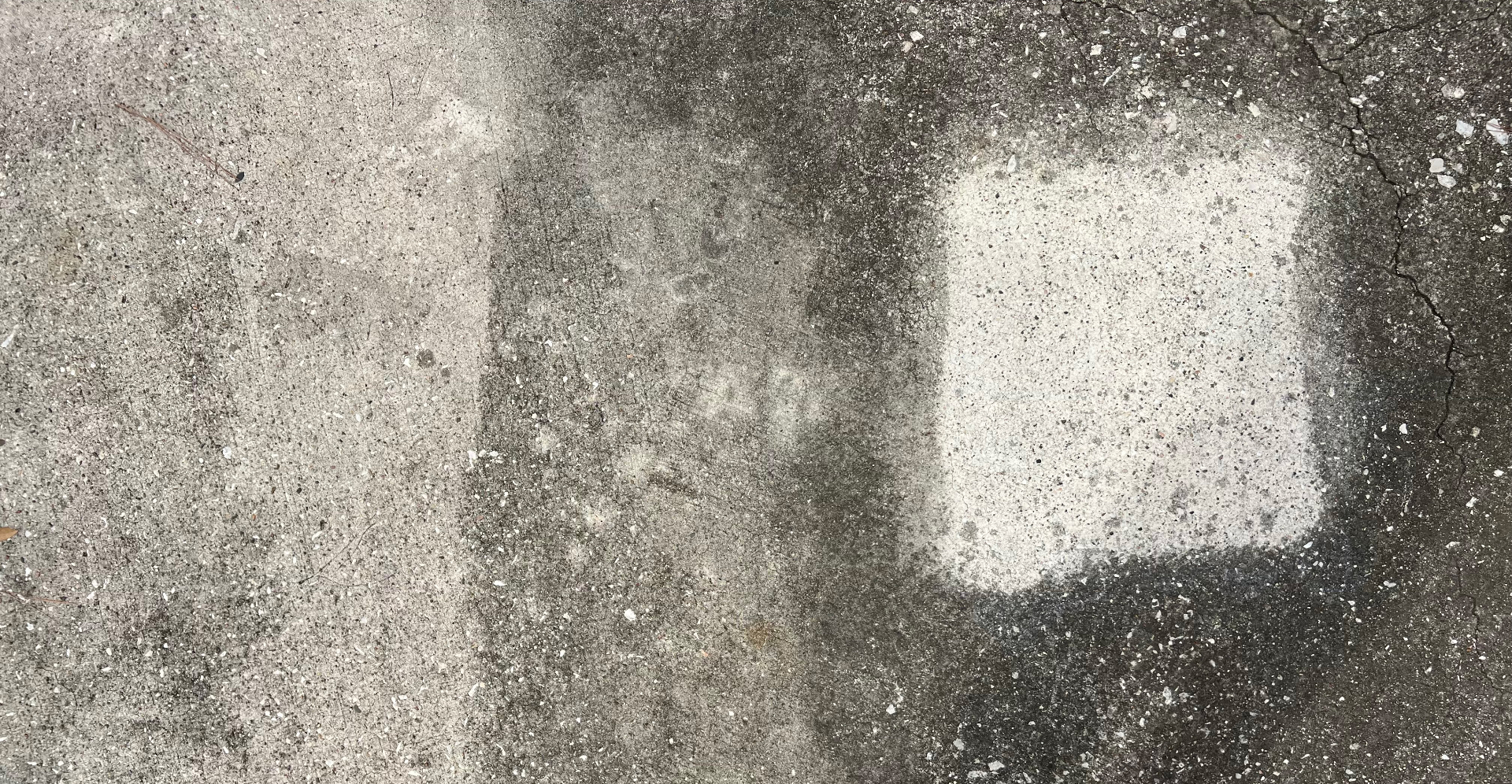 Macro close-up of concrete patio after 33 months, with bright untouched double-coat test square visible against weathered surrounding concrete
